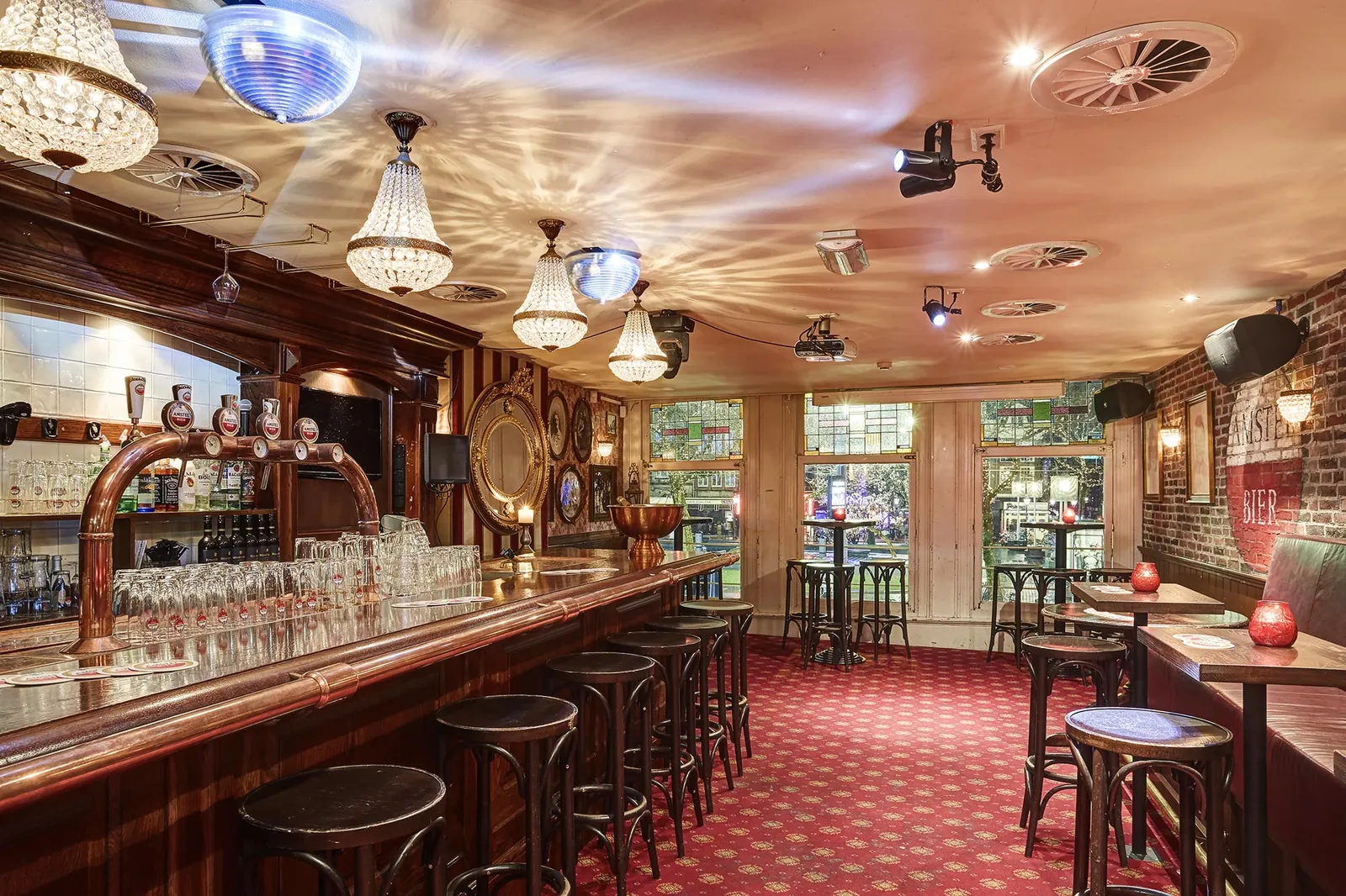 The first floor of Café Tante Roosje, with chandeliers and the Heineken wall